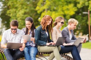 High school students sitting on a bench on their laptops