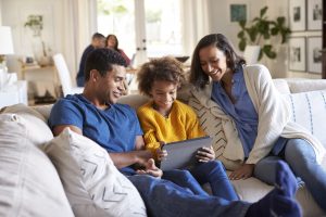 Parents sitting on the couch with their child looking at a smart device