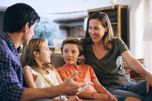 family-talking-3-scaled Parents sitting on the couch with their child looking at a smart device